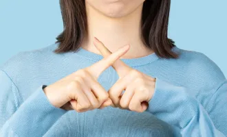 青い服を着た人が手で×を表現した画像