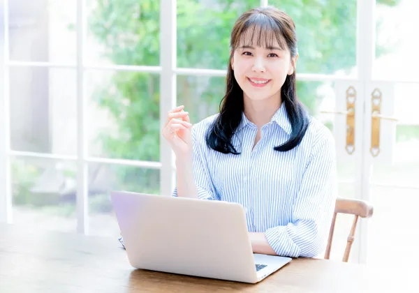 パソコンの前に座る自信がついて笑顔の女性の画像
